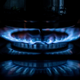 A flame on a gas stove with a pot sitting above it.